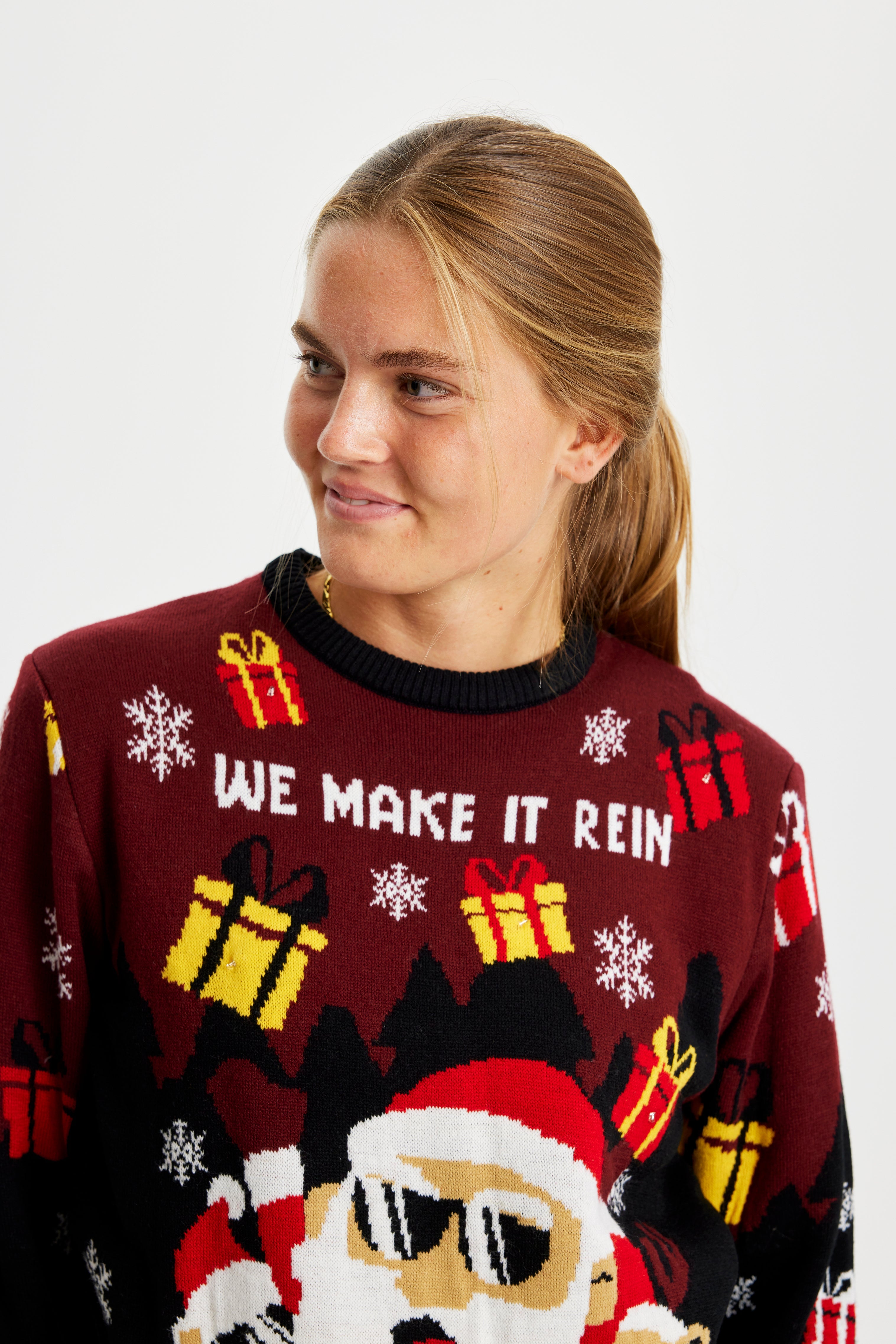 En kvinde iført en mørkerød julesweater med gaver på.