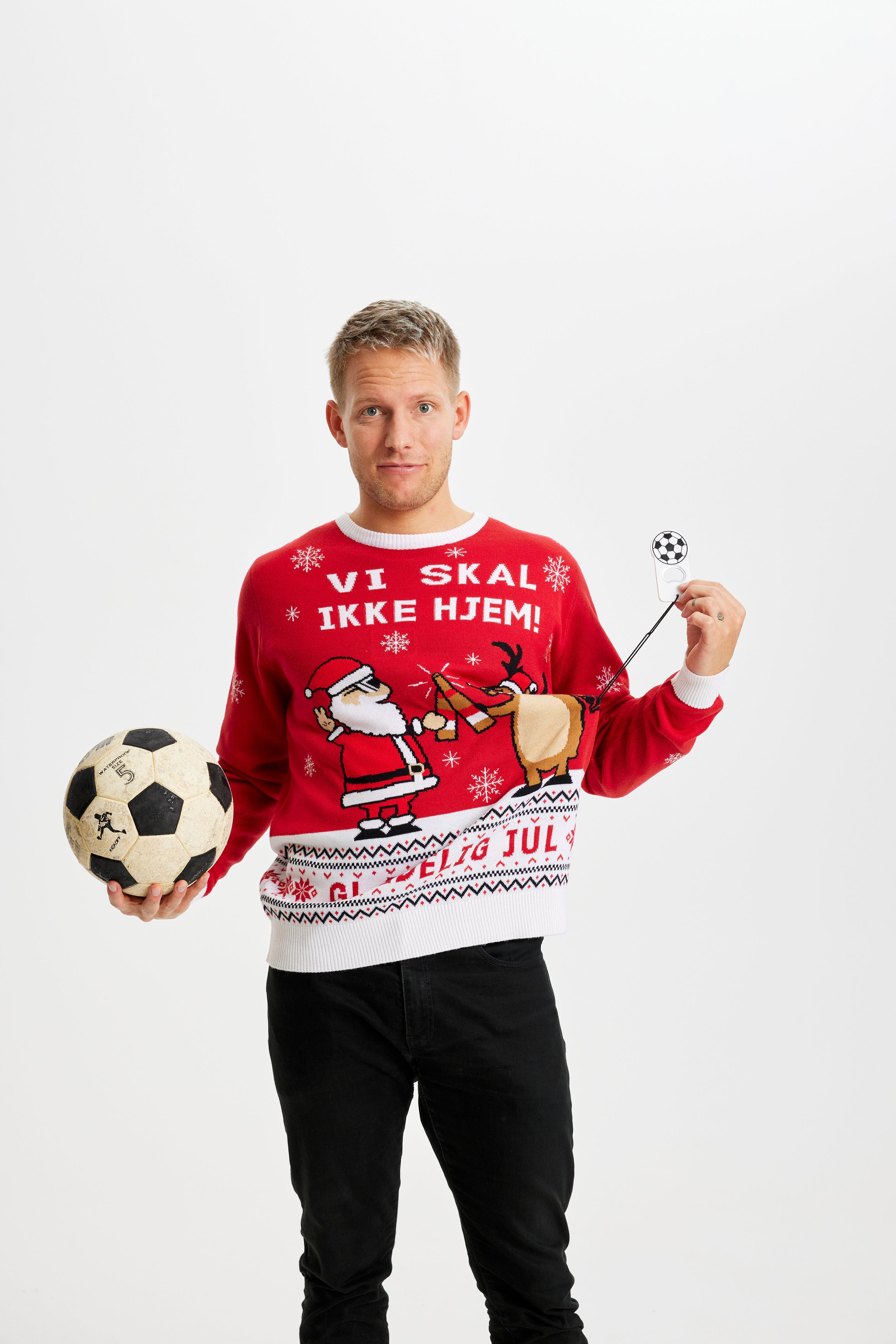 En mand poserer med en fodbold og i sin julesweater.
