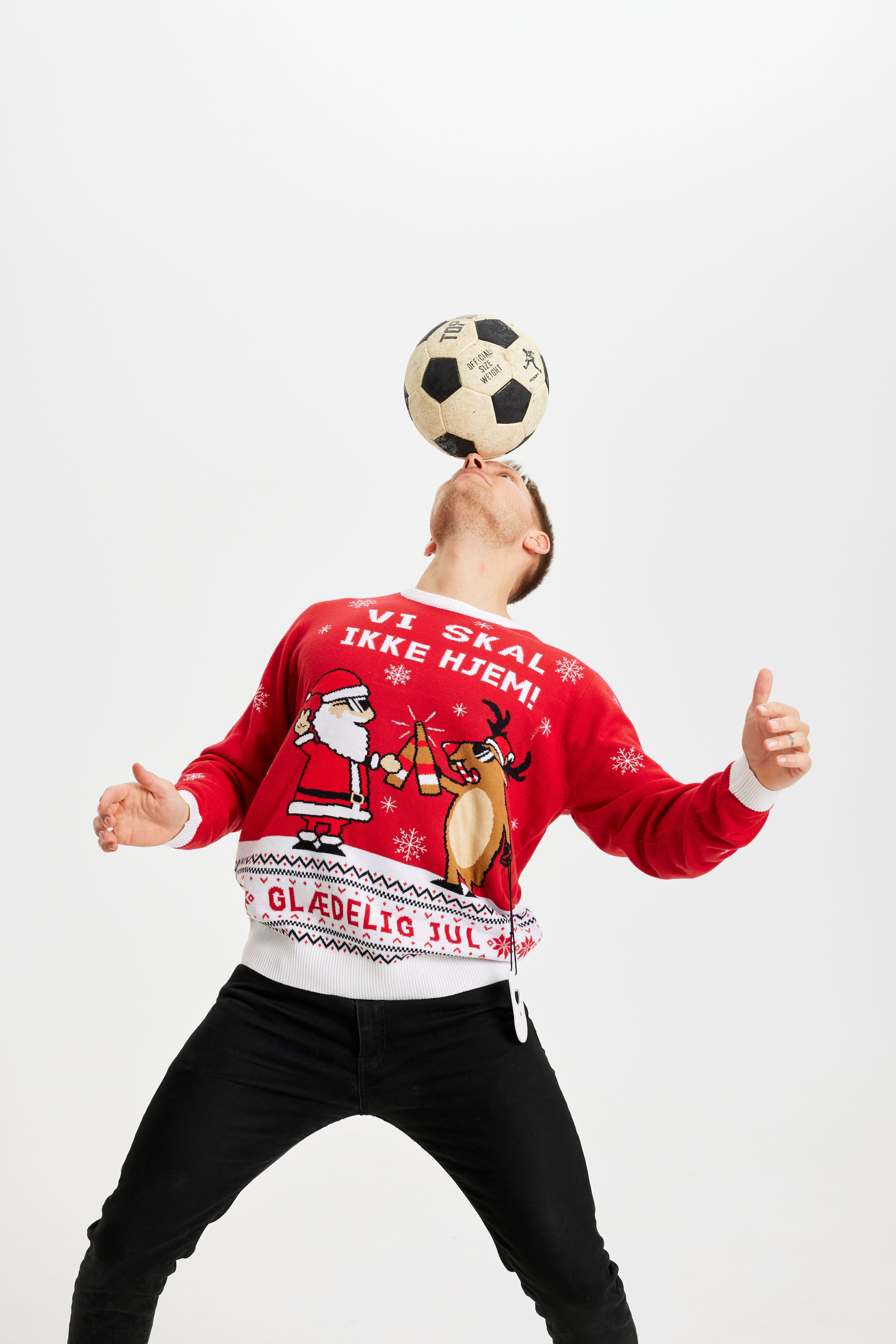 En mand med en fodbold iført en rød julesweater.