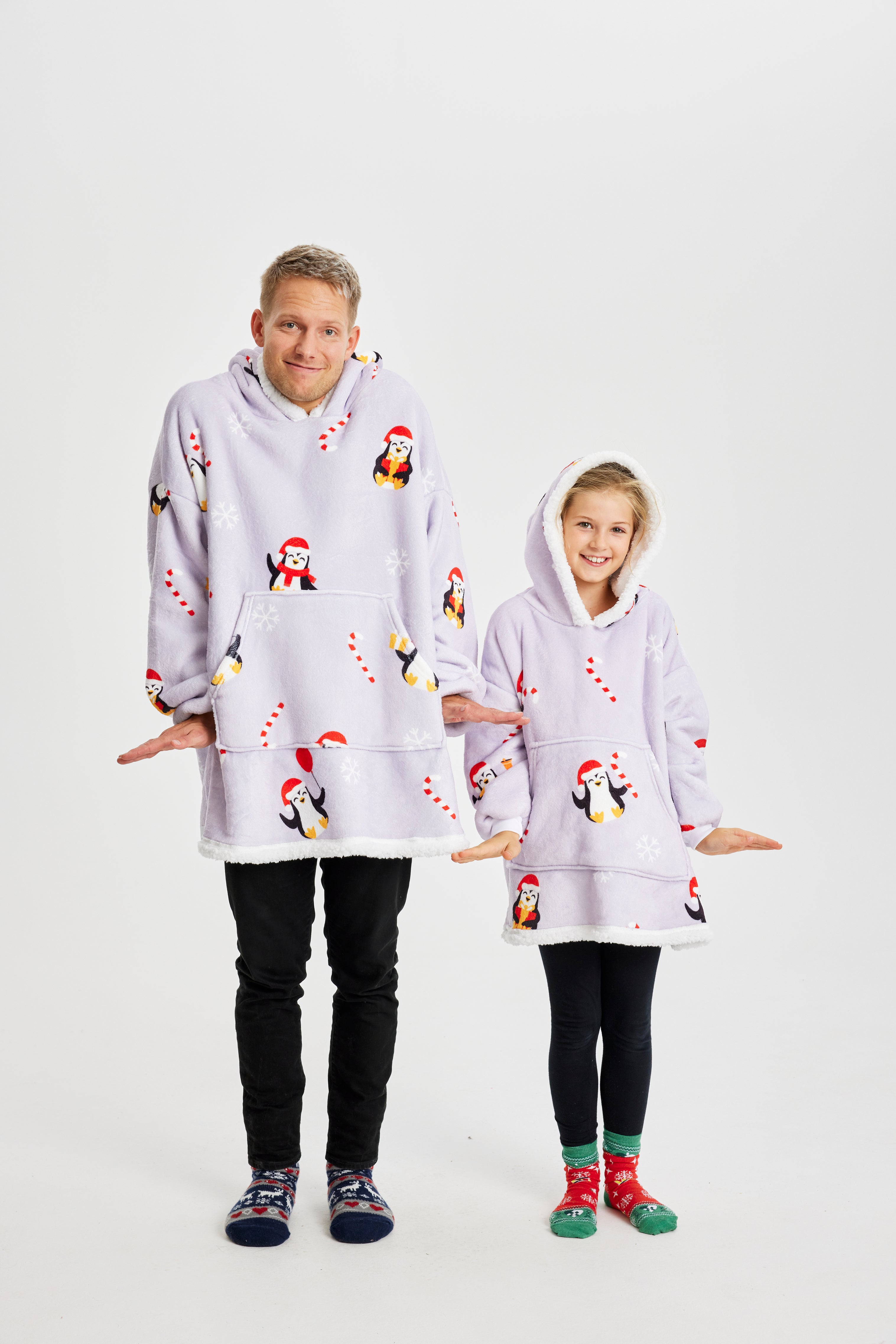 En mand og et barn poserer sammen i hver deres julehoodie med pingviner på.