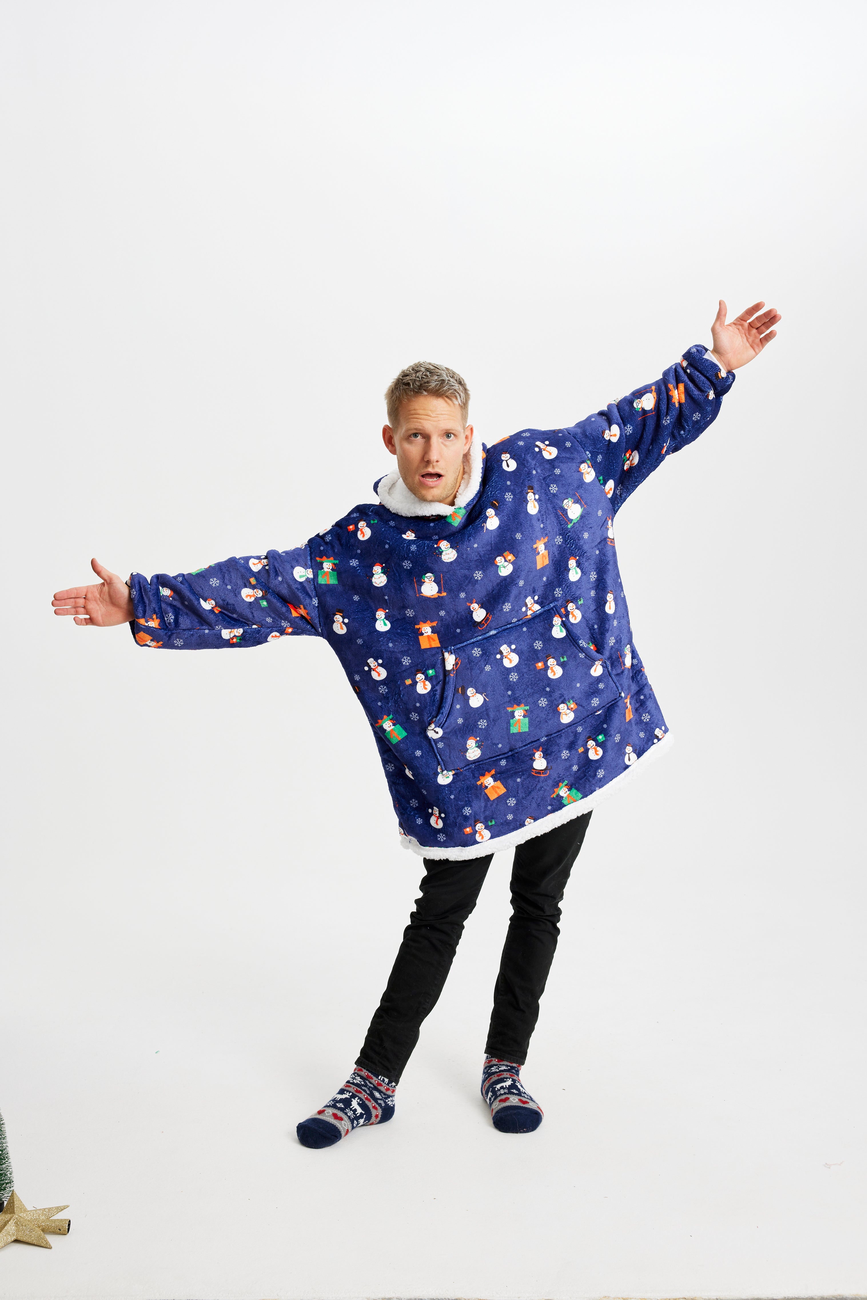 En mand med armene ud til siden iført en blå julehoodie.