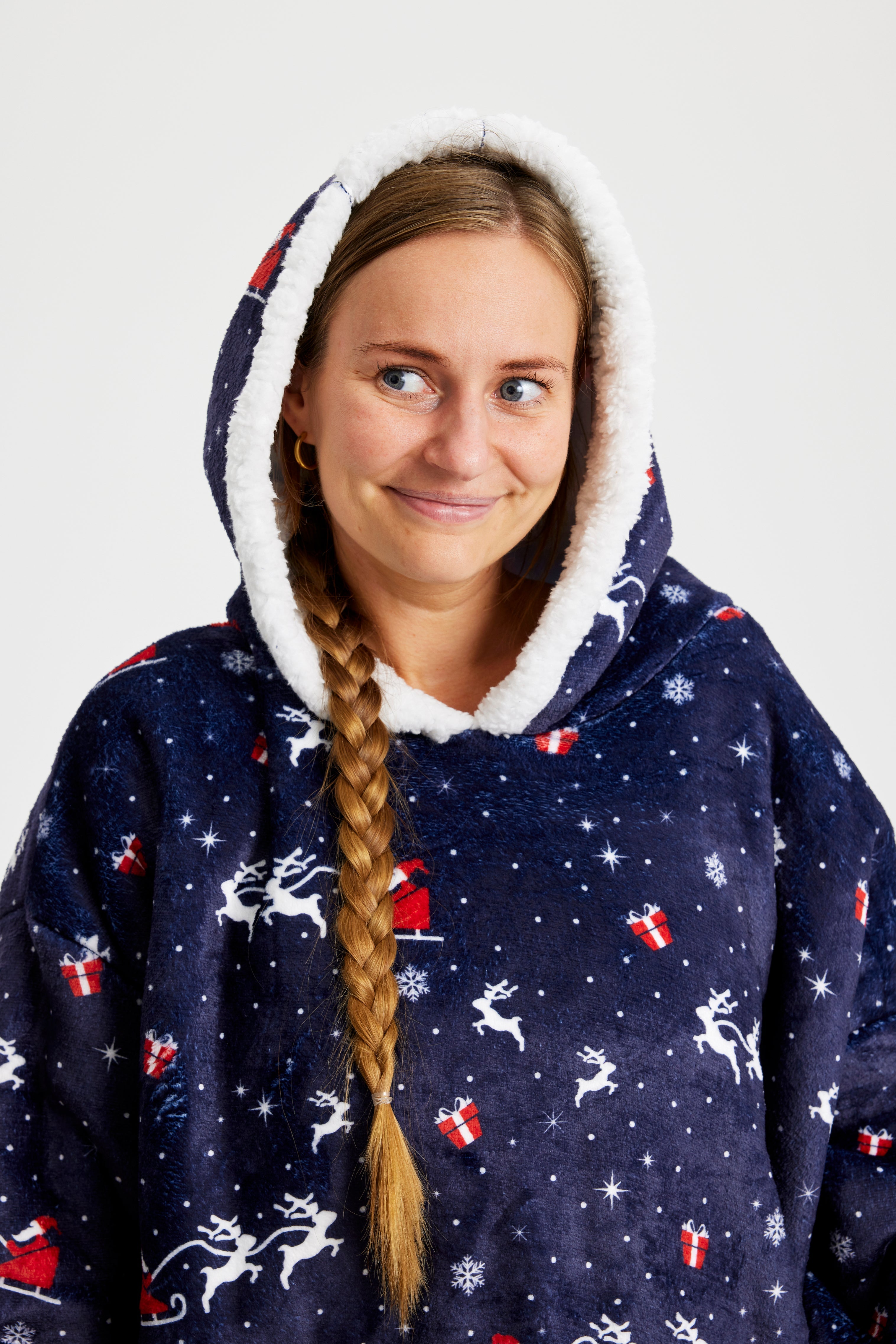 En smilende kvinde iført en dybblå julehoodie med rensdyr.