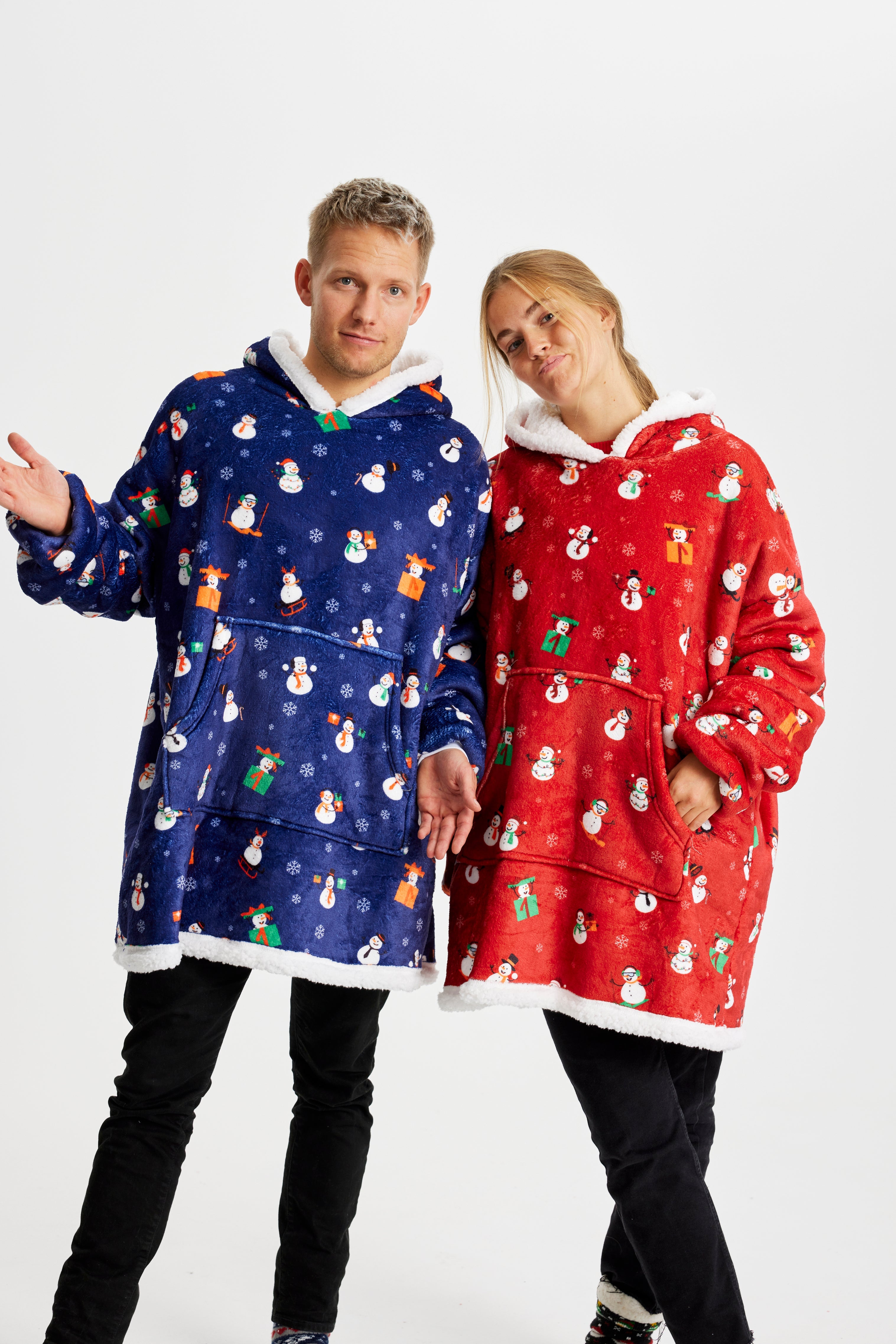 En poserende mand og kvinde iført en blå og en rød julehoodie.