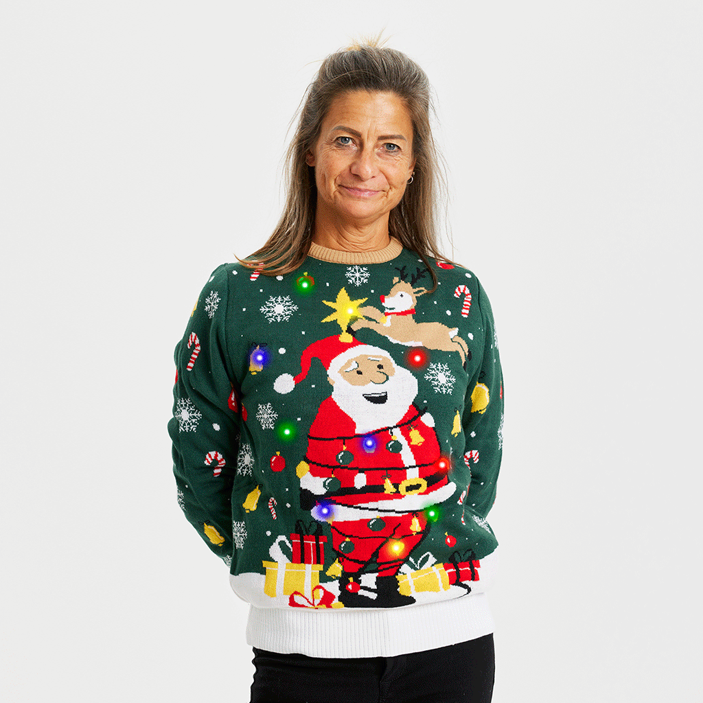 En kvinde iført en grøn julesweater med lys og snefnug på.