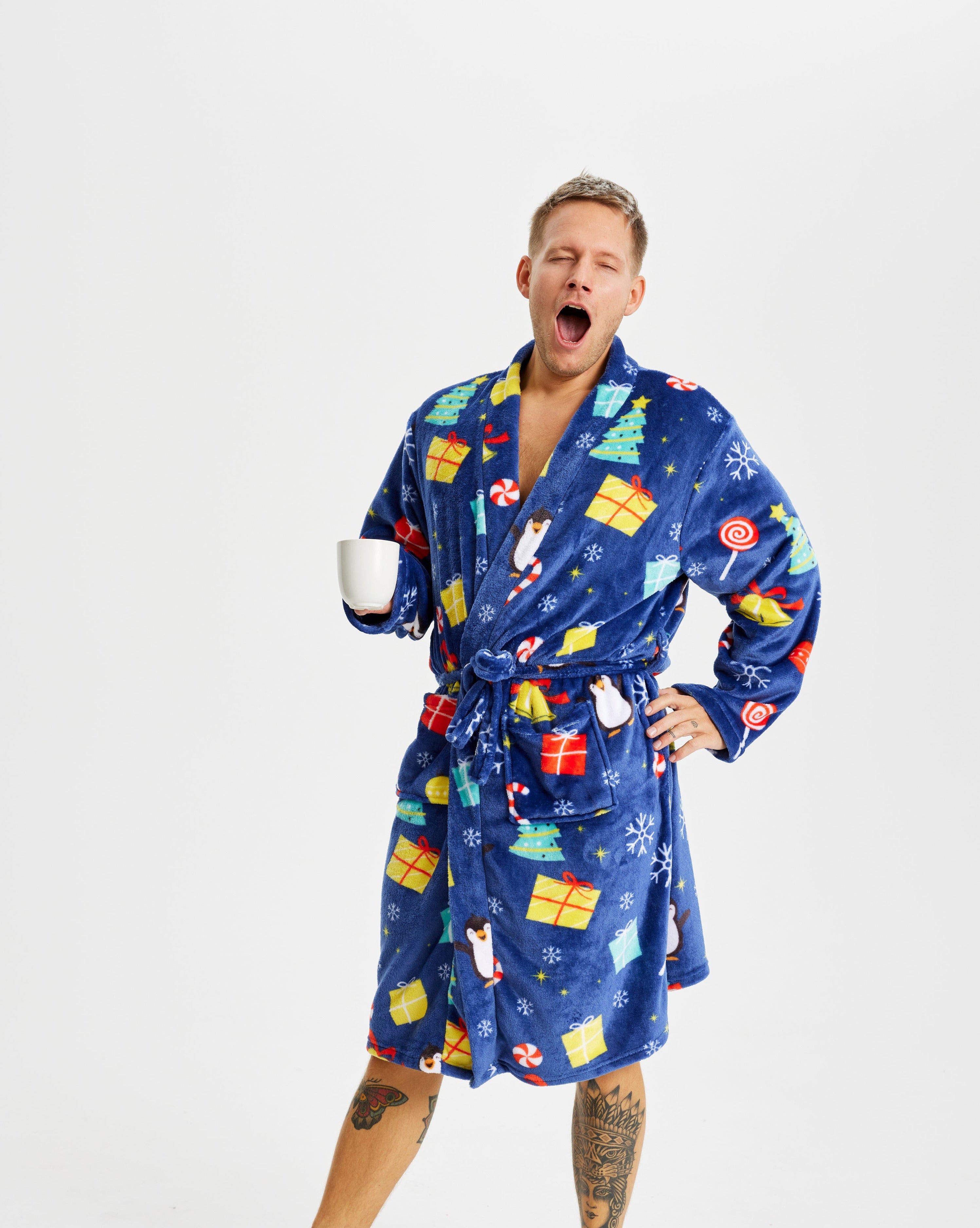 En gabende mand i julebadekåbe med en kop i hånden.
