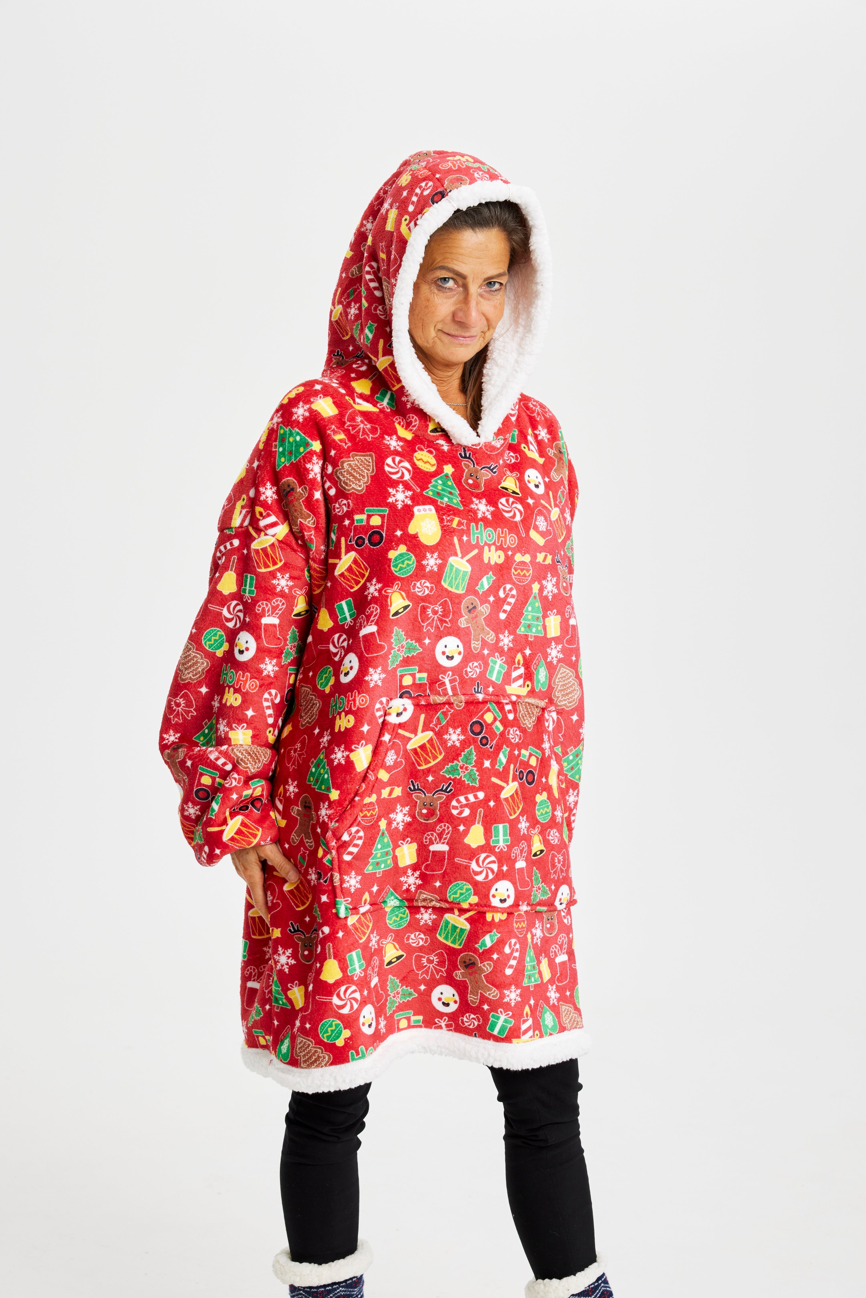 En dame iført en rød julehoodie med vanter, juletræer, kagemænd, juleslik og trommer.