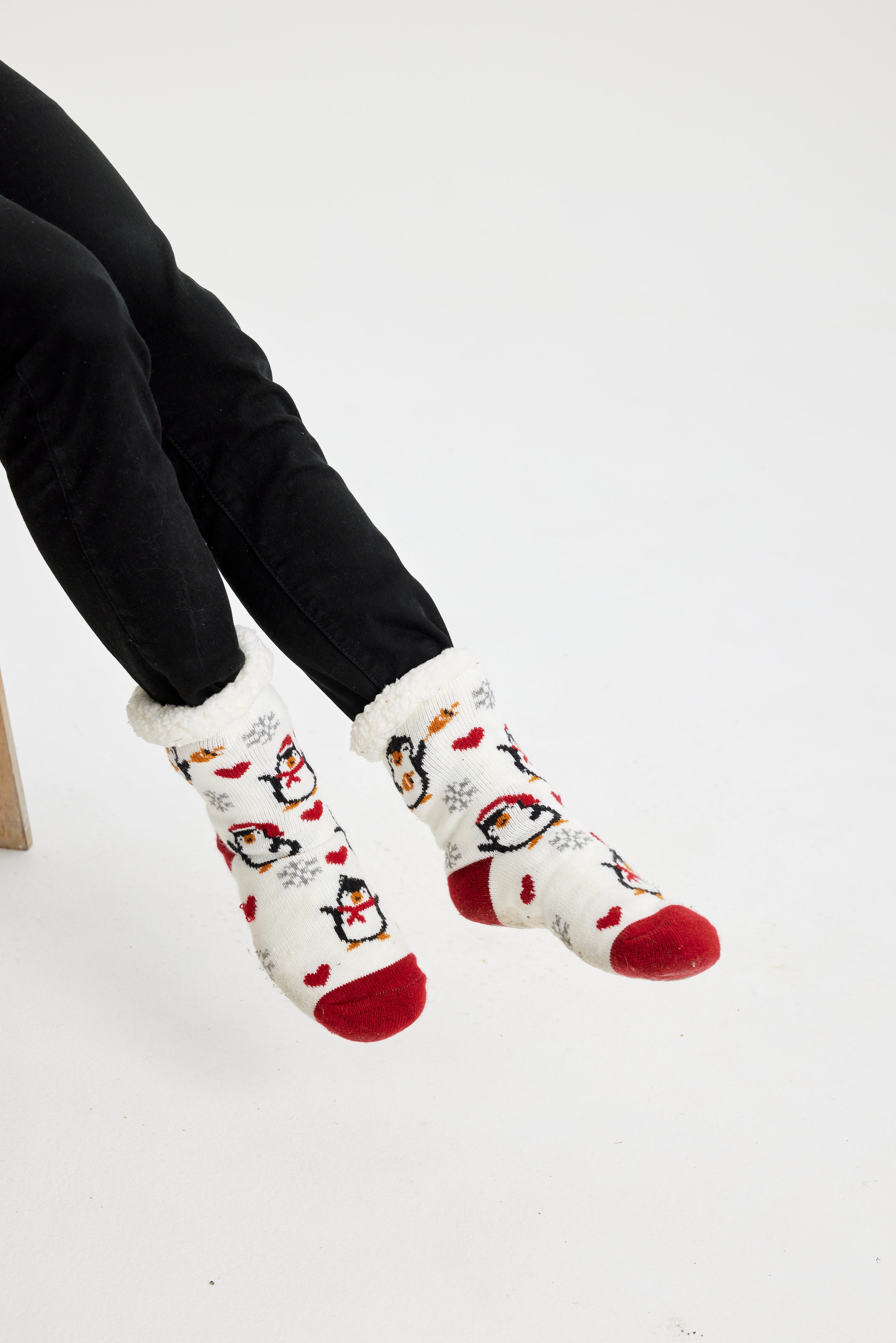 Et par røde og hvide sokker i juletemaer med pingviner.