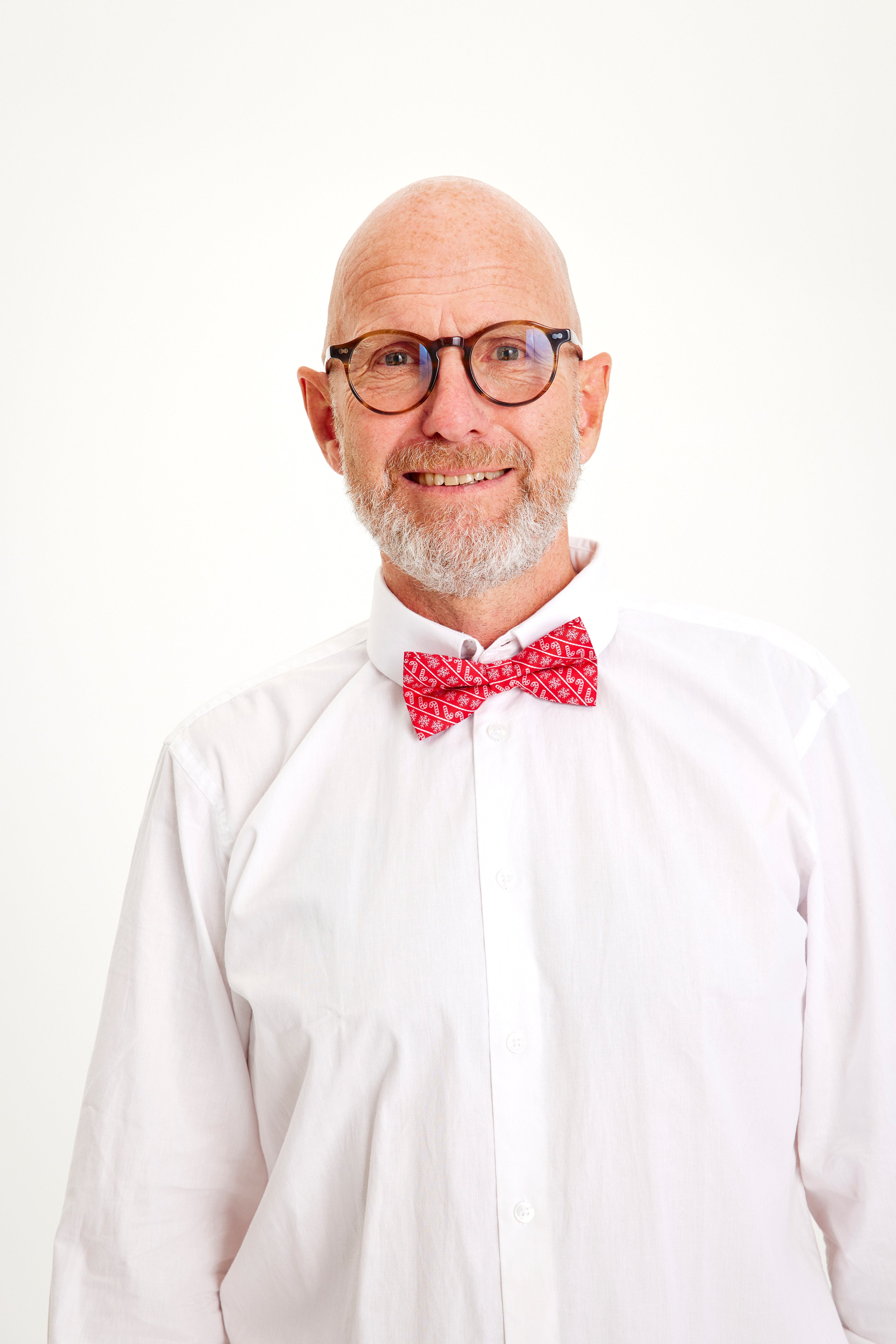 En smilende mand iført en hvid skjorte og en fin julebutterfly.