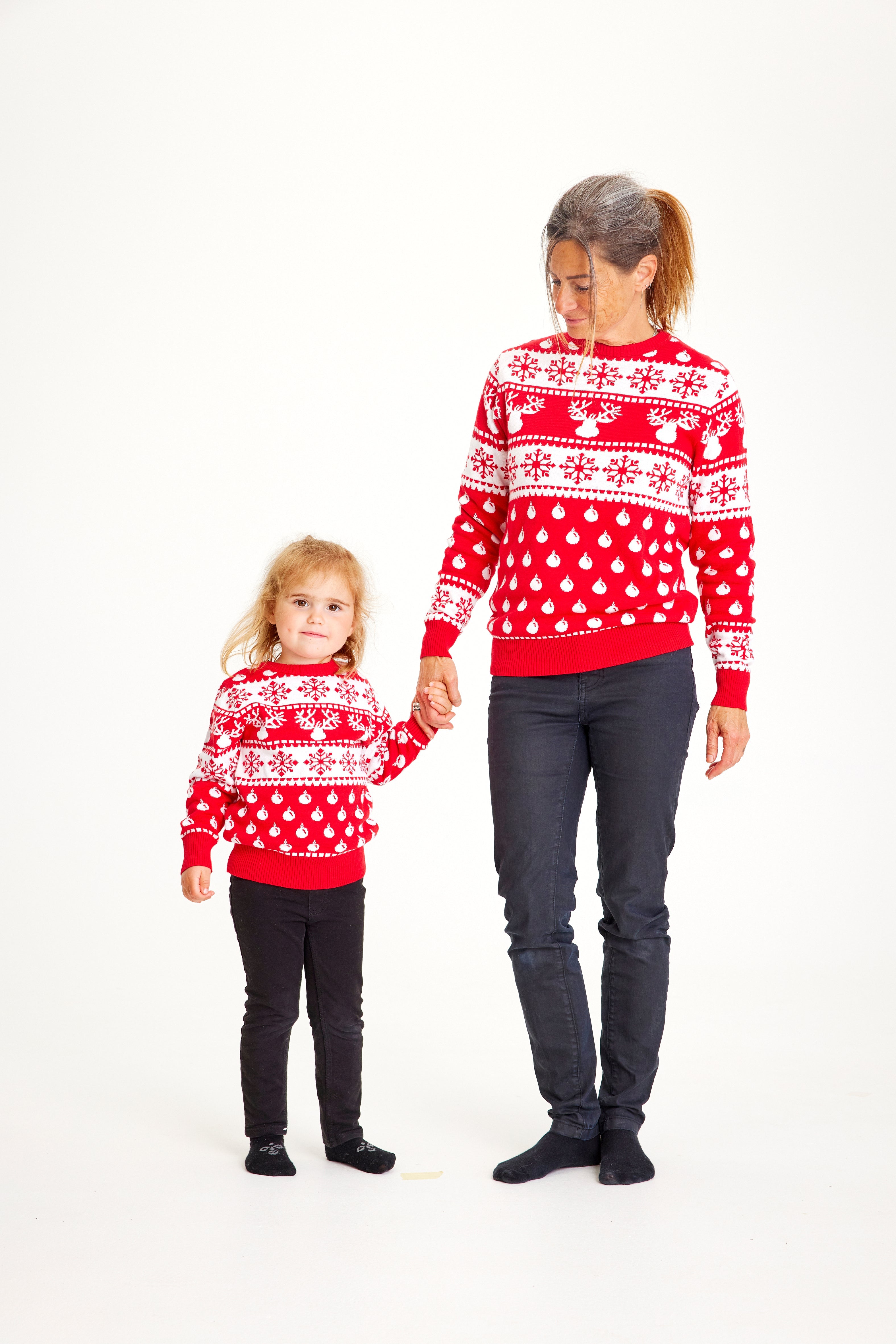 En dame og et barn poserer i røde julesweatre med mønster.