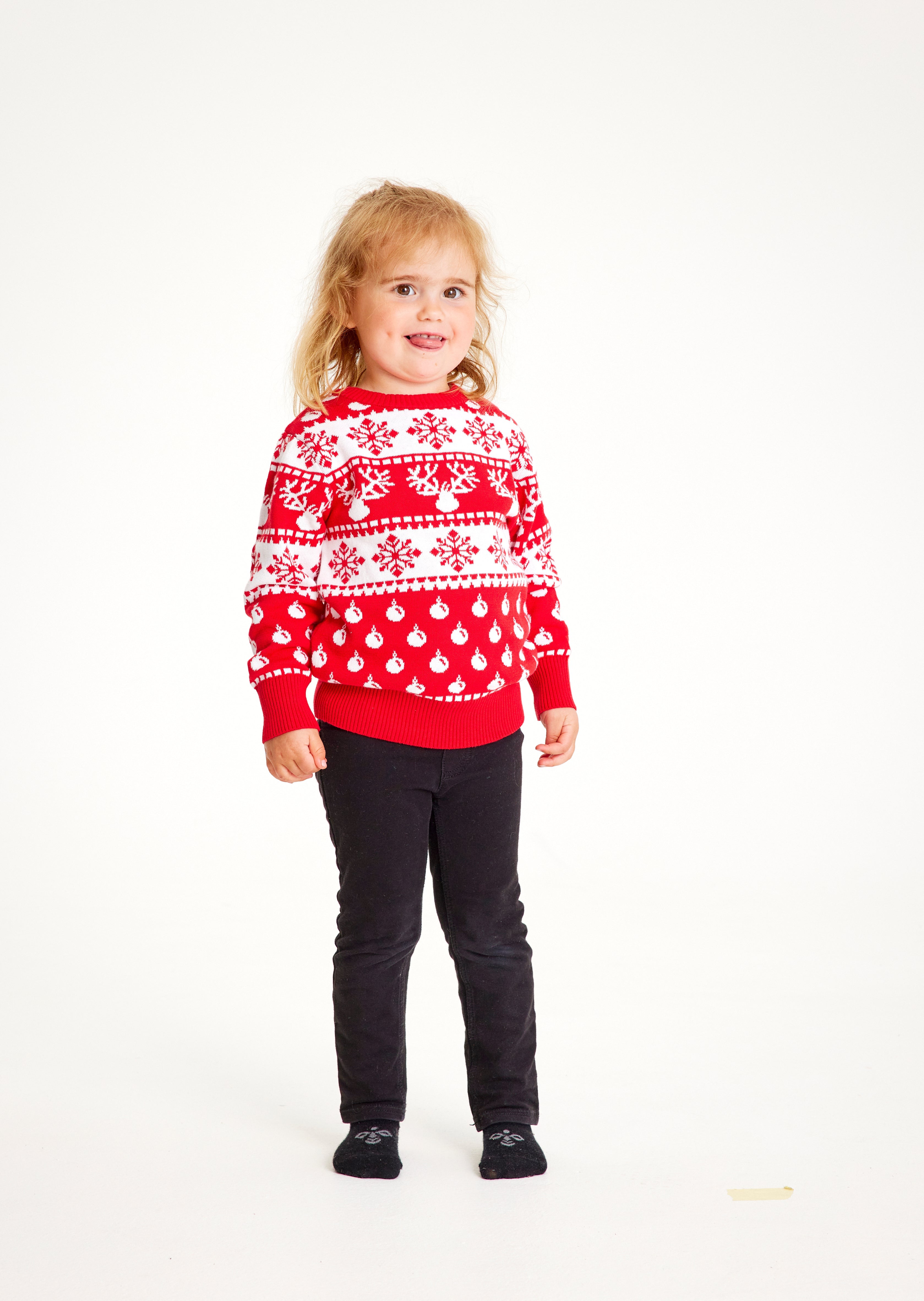 Et sødt barn iført en klassisk, rød julesweater med mønster.