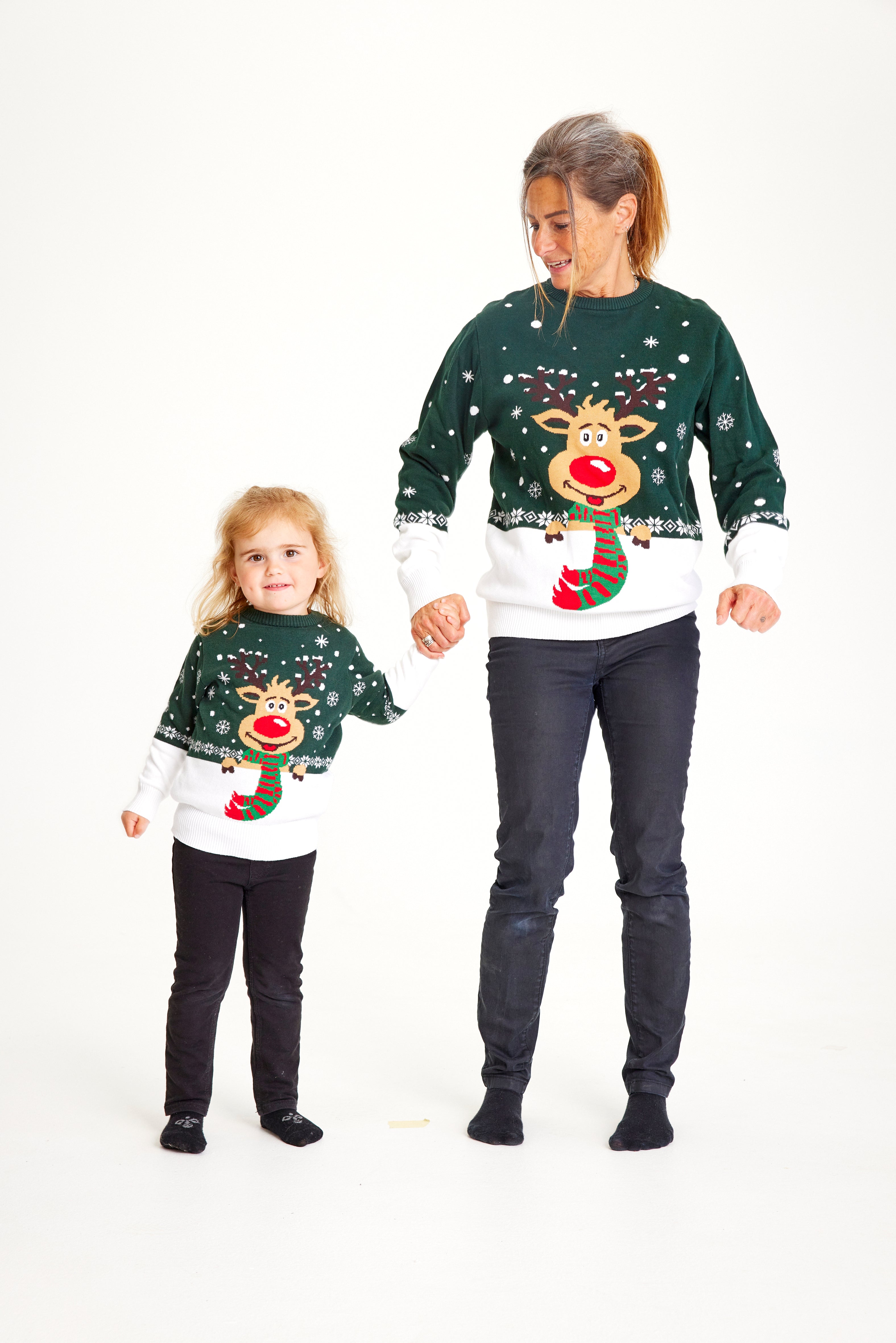 Et barn og en dame iført grønne julesweatre med snefnug og Rudolf på.