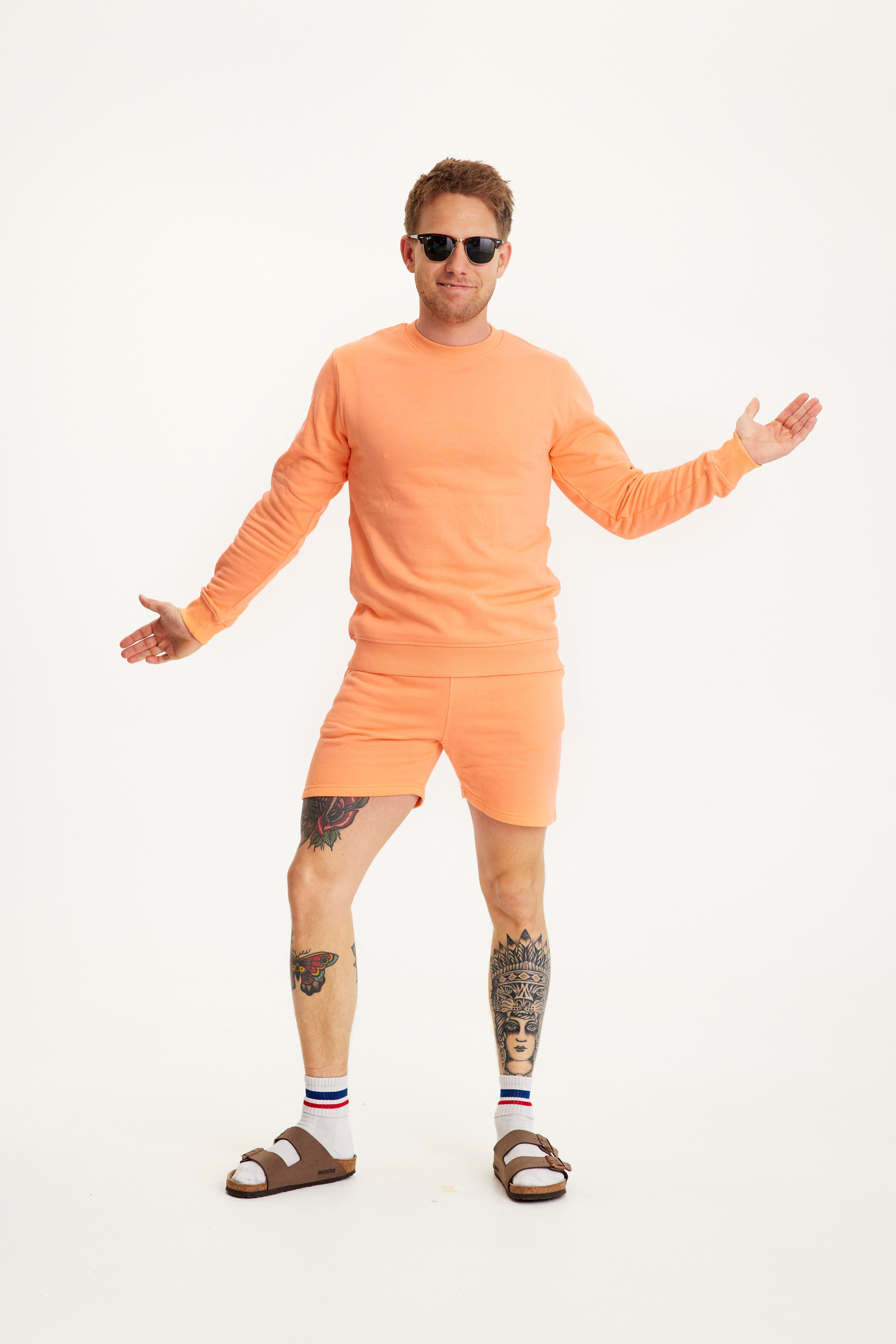 En mand i solbriller iført et ferskenfarvet sommersæt.