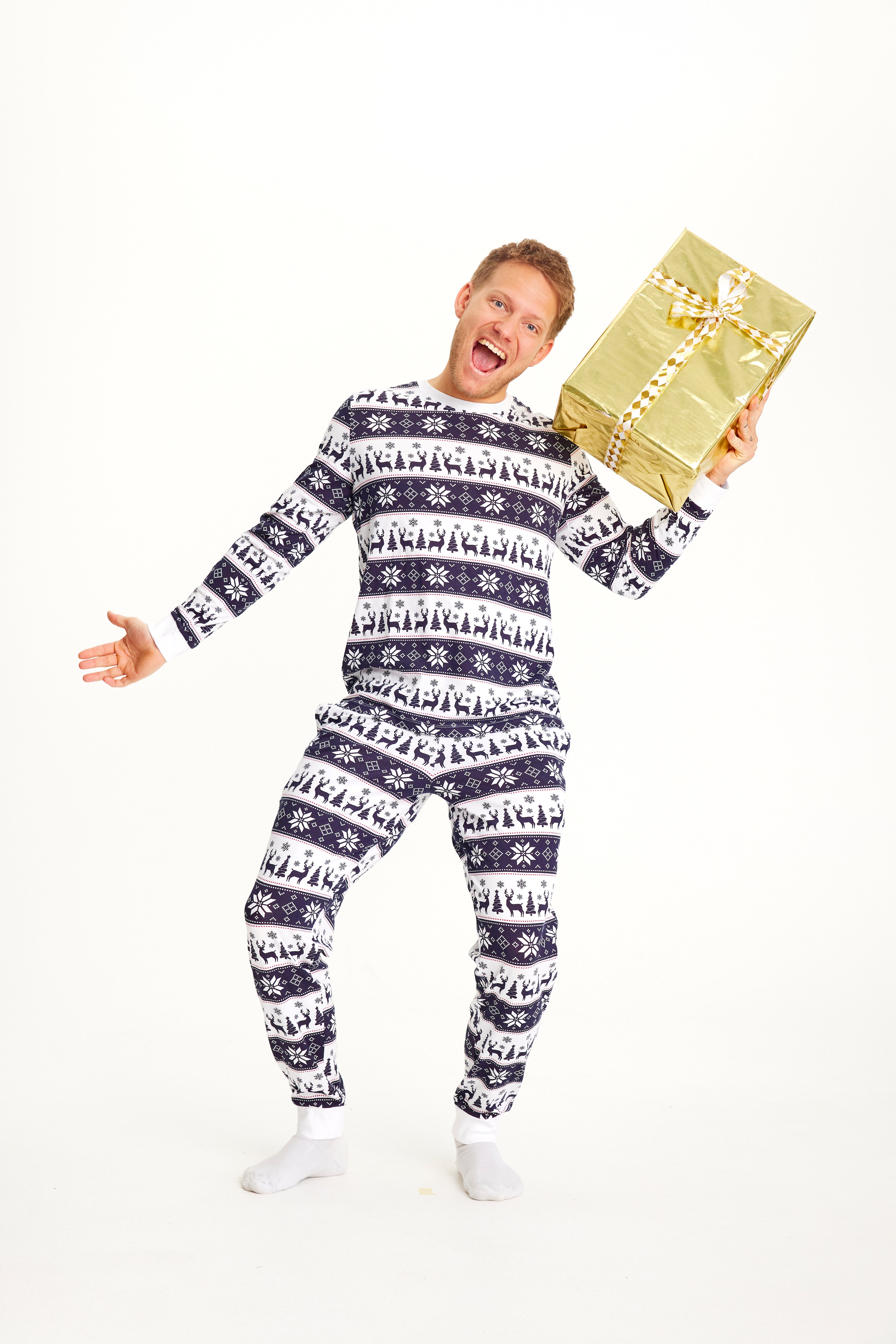 En mand med en gave i den ene hånd iført julepyjamas med rensdyr på.