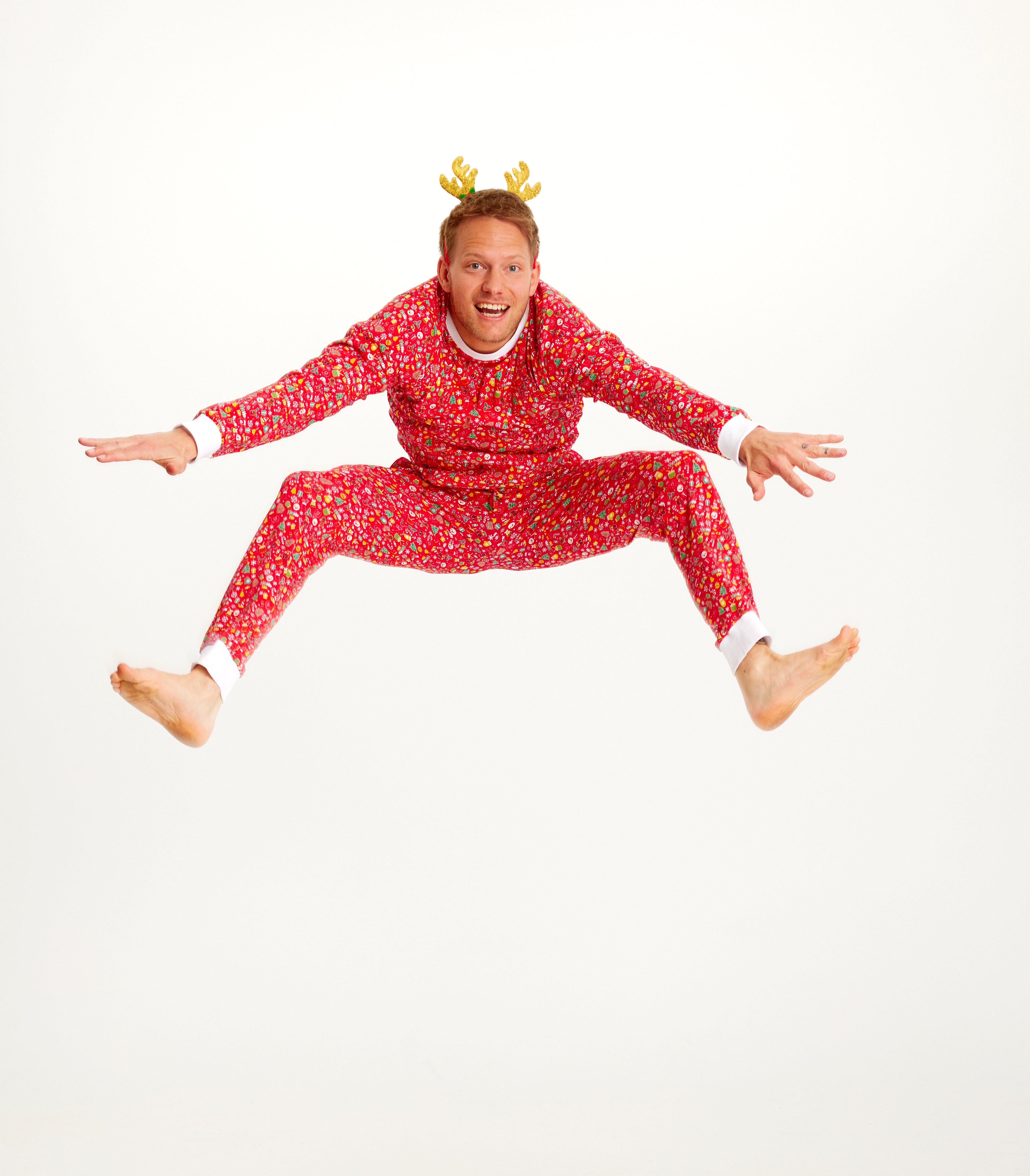 En hoppende mand er iført en rød julepyjamas.