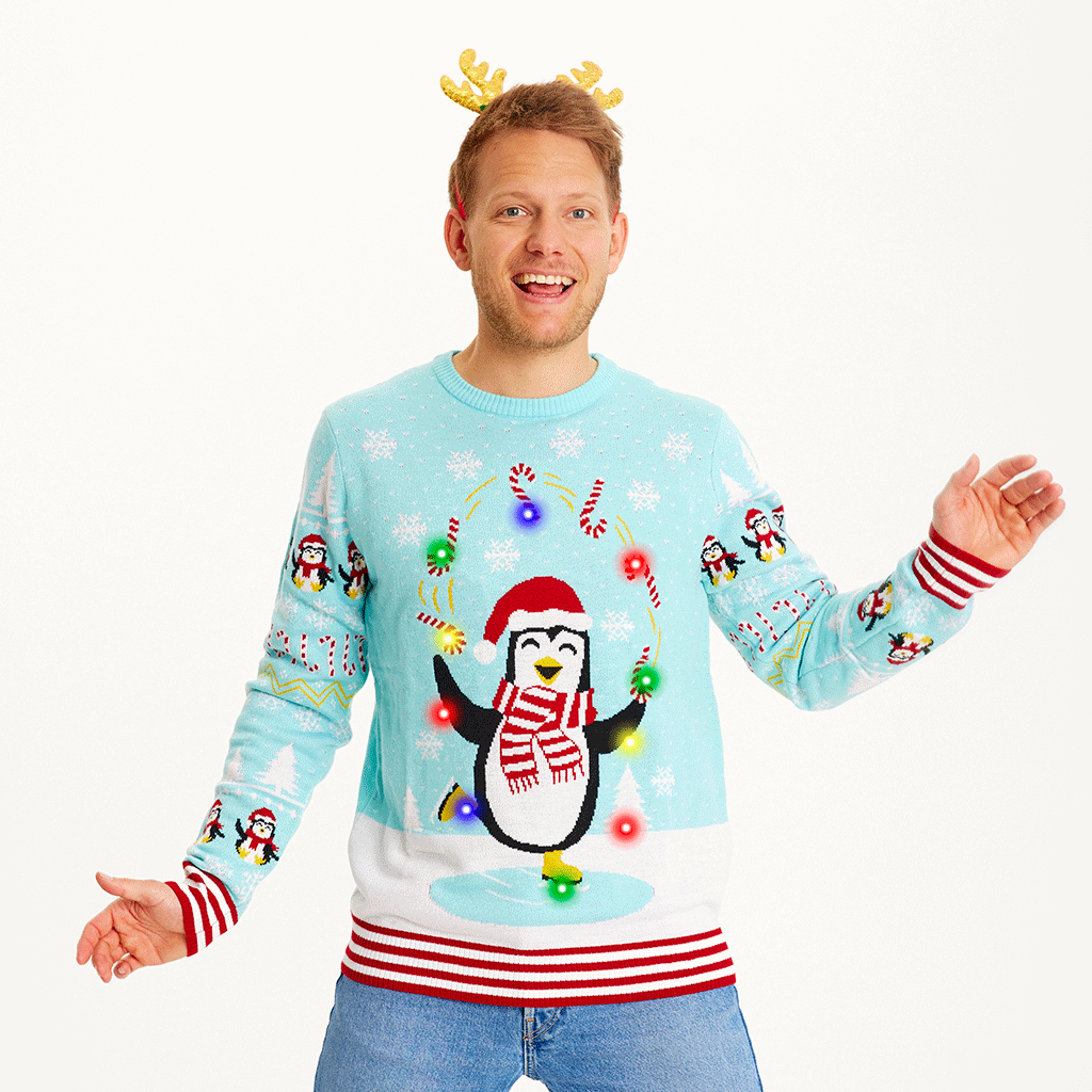 En smilende mand iført rensdyrgevir og en julesweater med pingviner på.