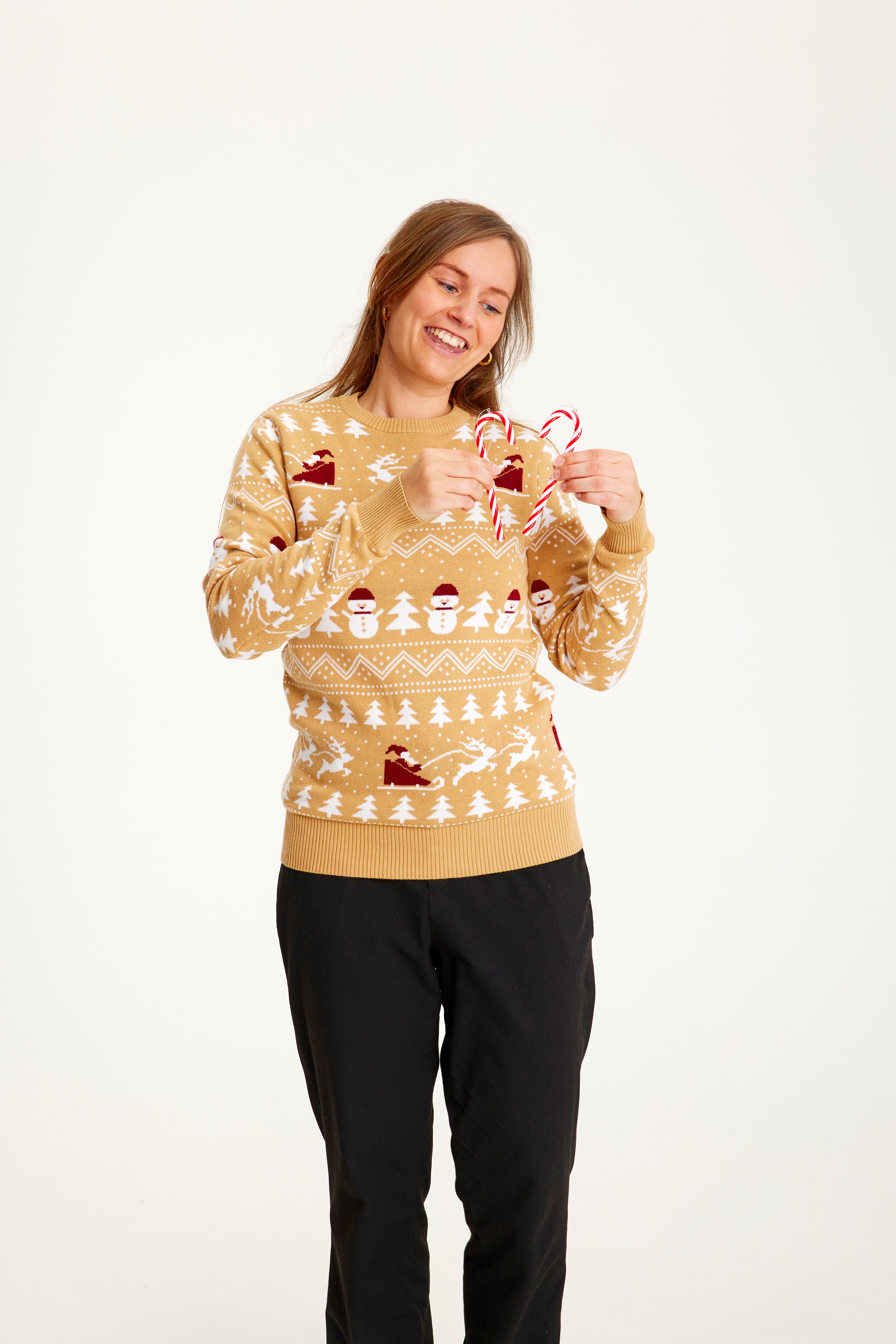 En smilende kvinde poserer i en beige julesweater.