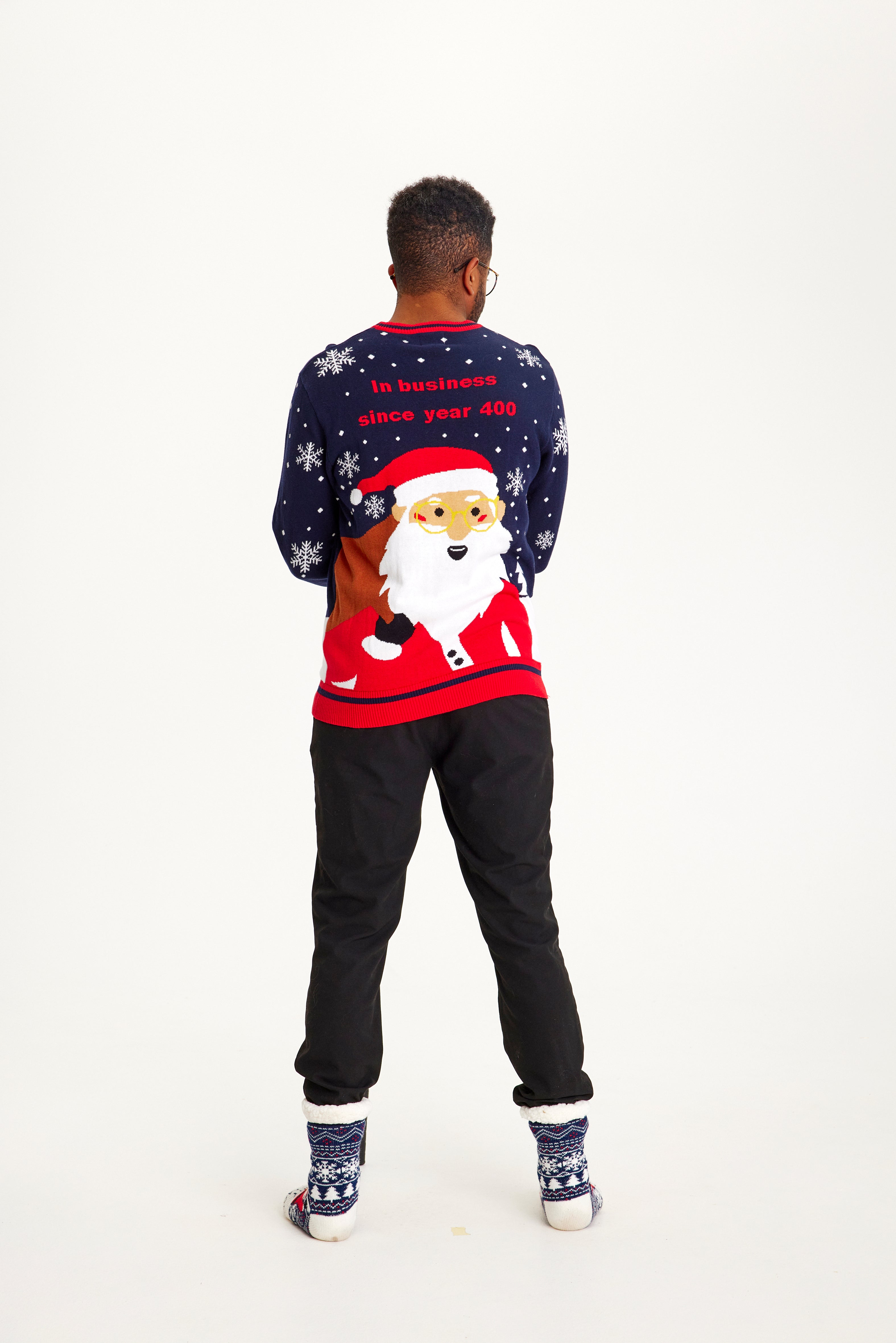 En mand står med ryggen til og er iført en julesweater.
