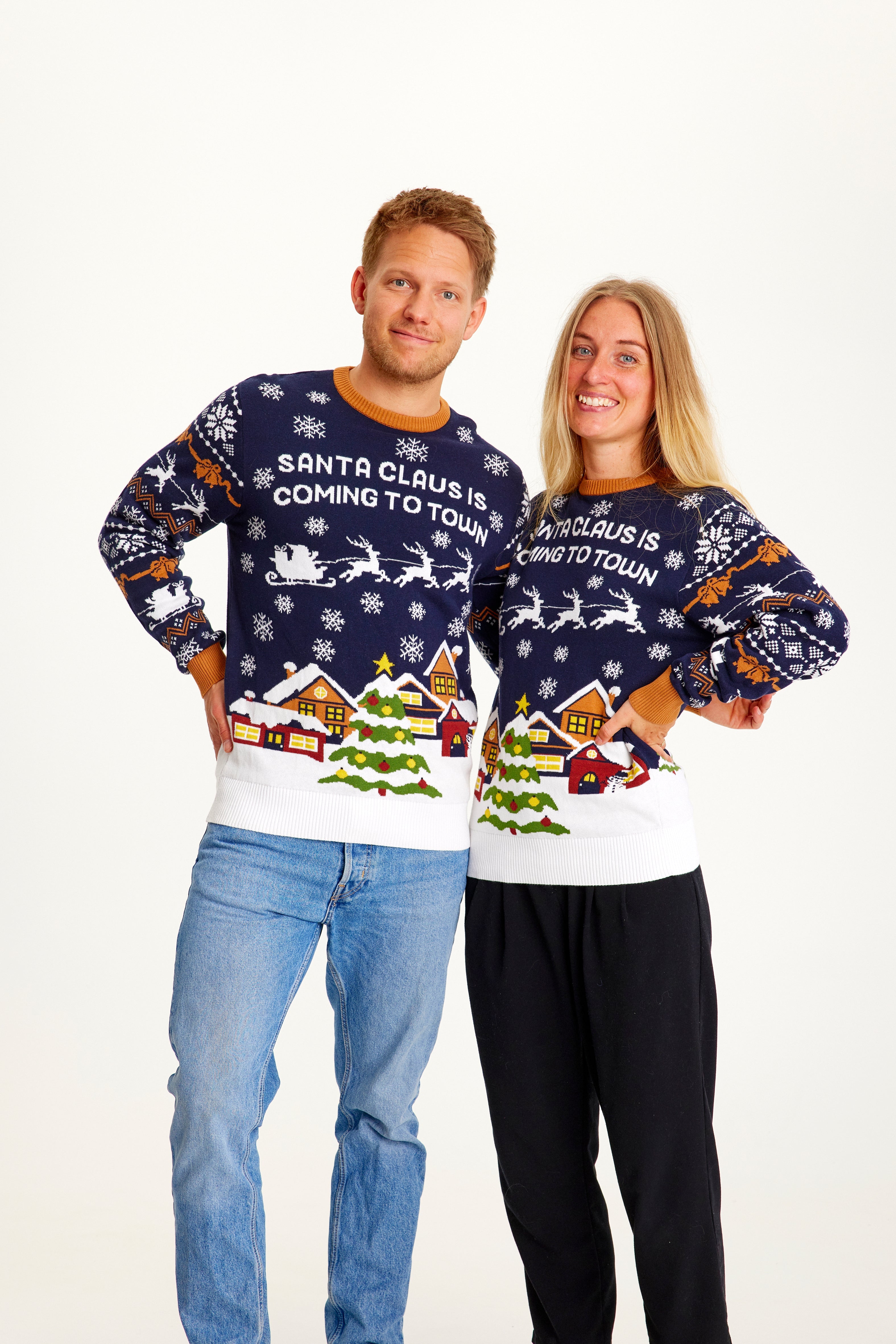 Et smilende par iført en julesweater med citatet 