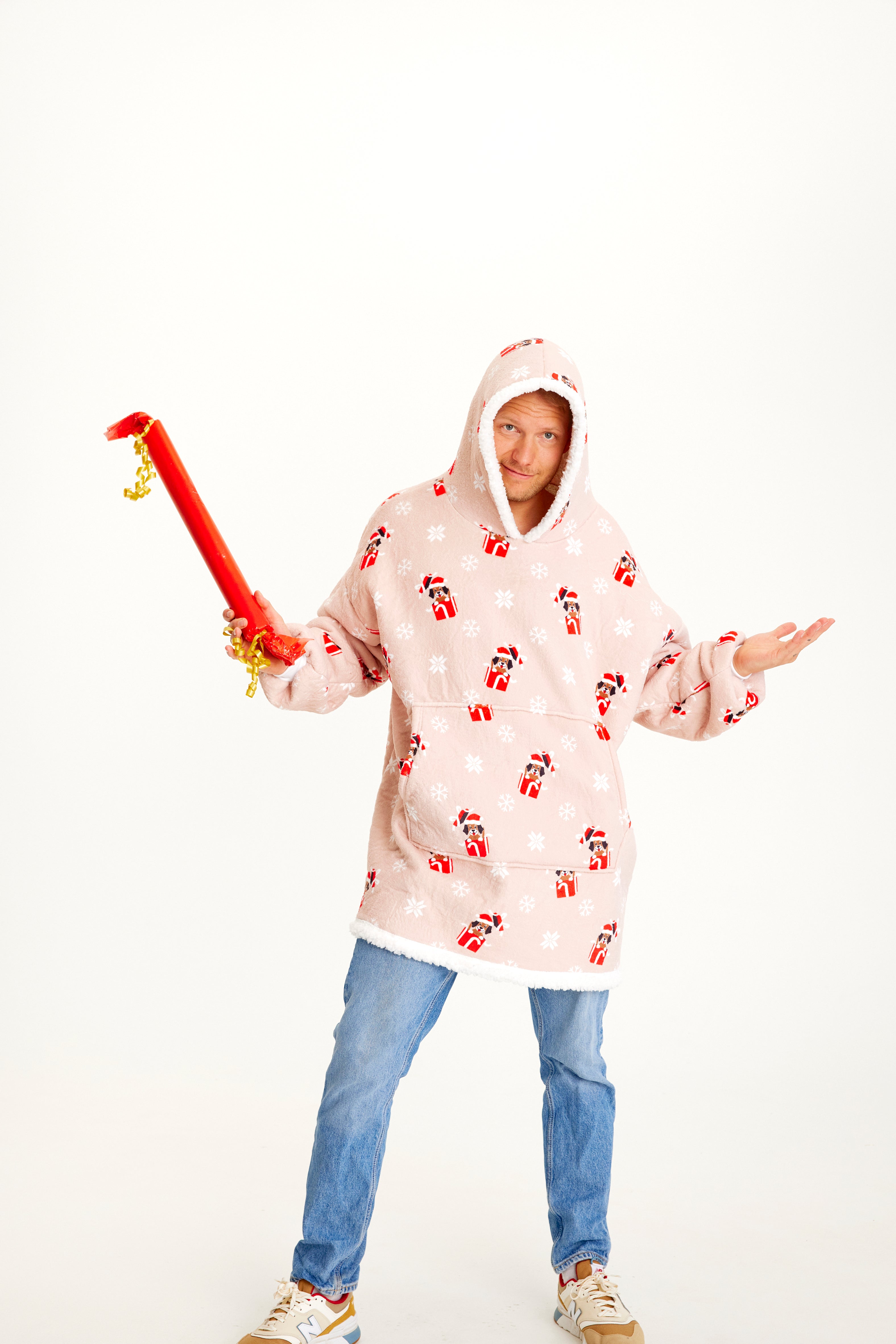 En mand med en gave i den ene hånd er iført en julehoodie med hunde.