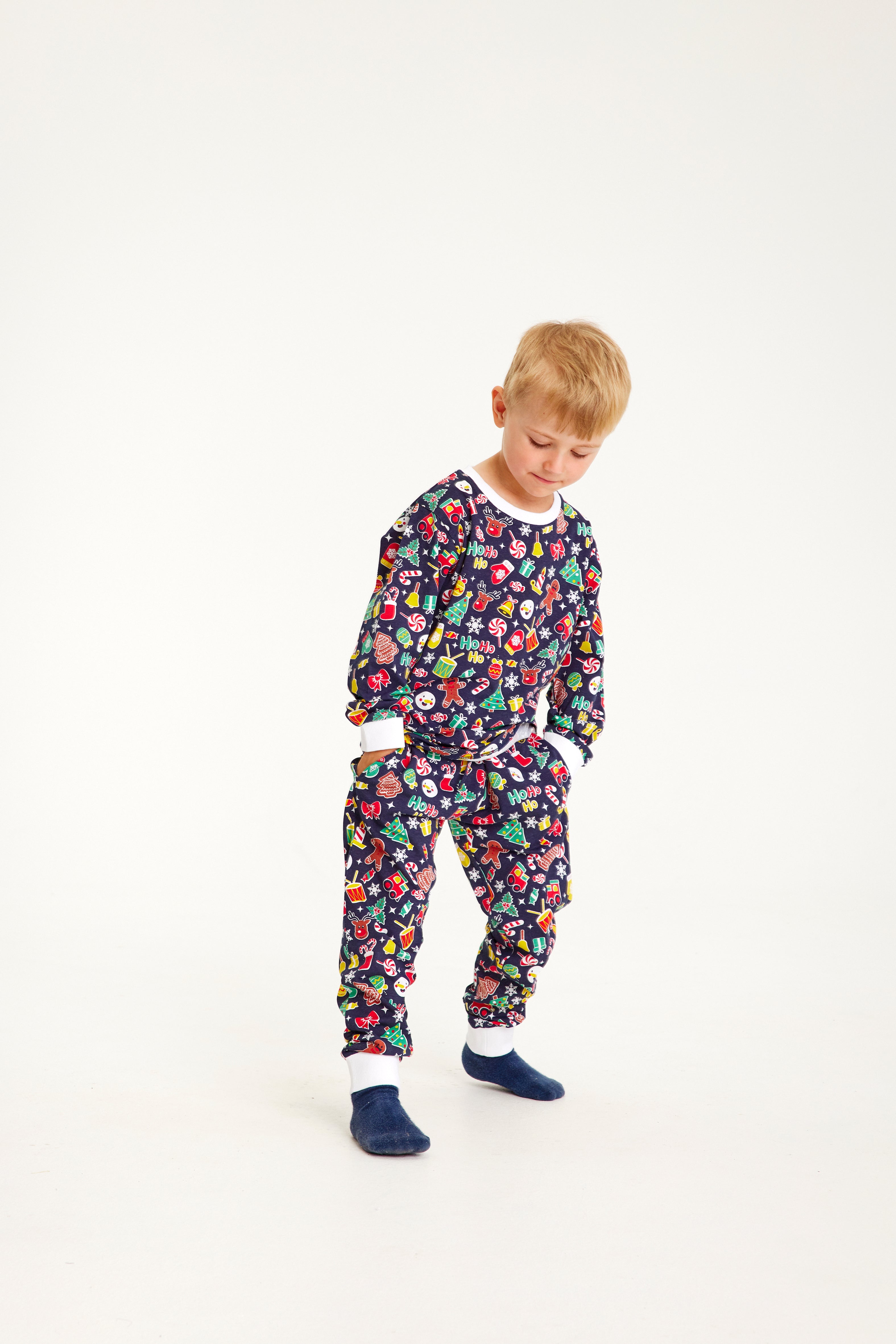 En barn er iført en blå julepyjamas med julemønster på.