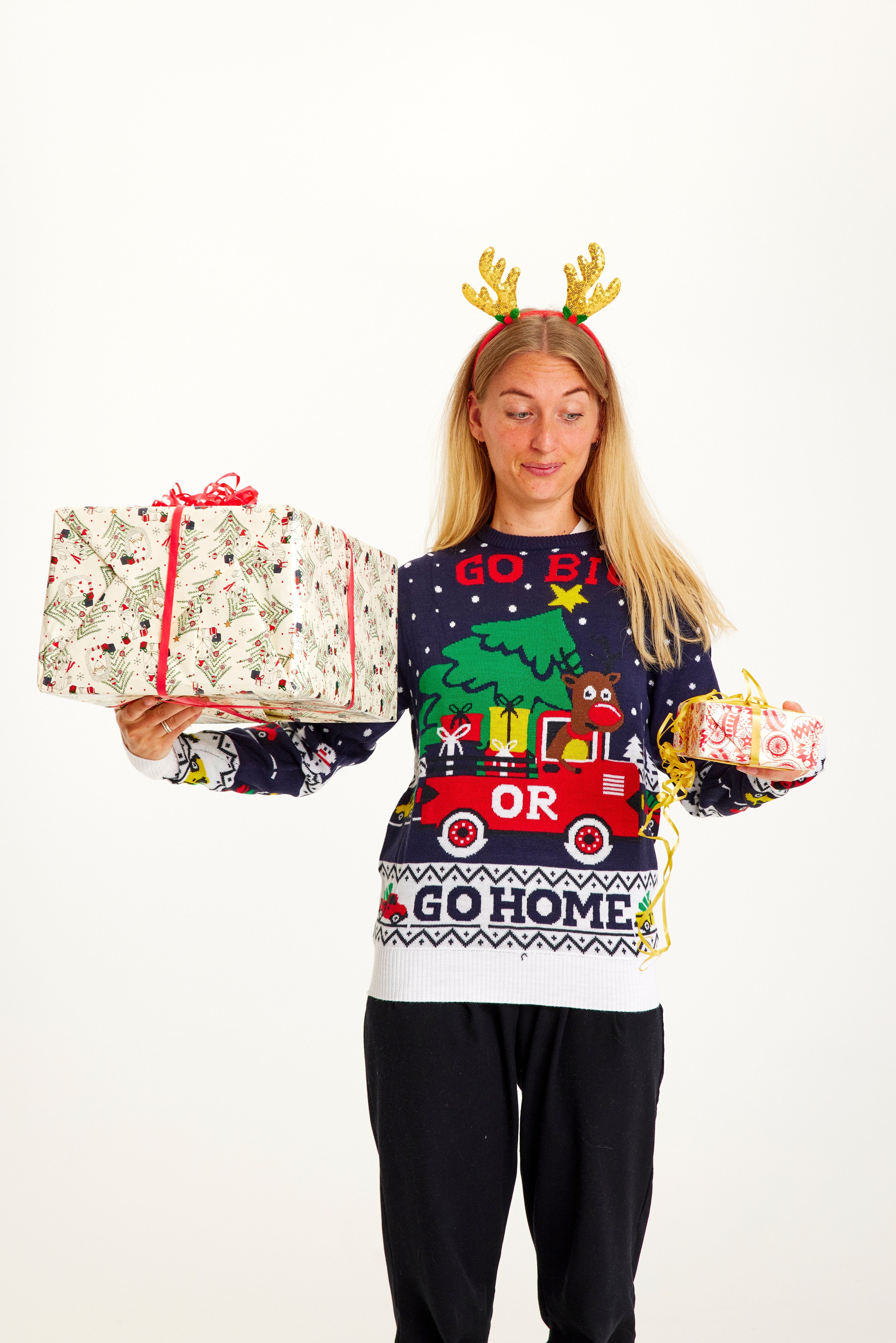 En dame der står med gaver iklædt en julesweater.