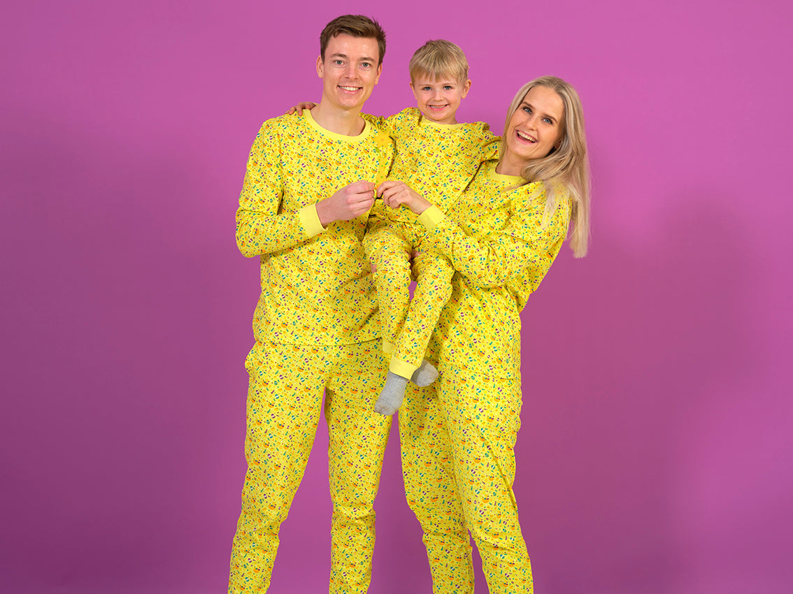 En familie smiler, mens de står i gule påskepyjamas.