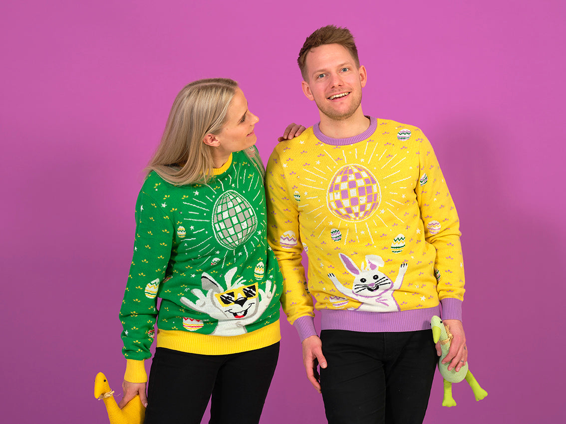 En mand og en dame iklædt hver deres påskesweater i forskellige farver.