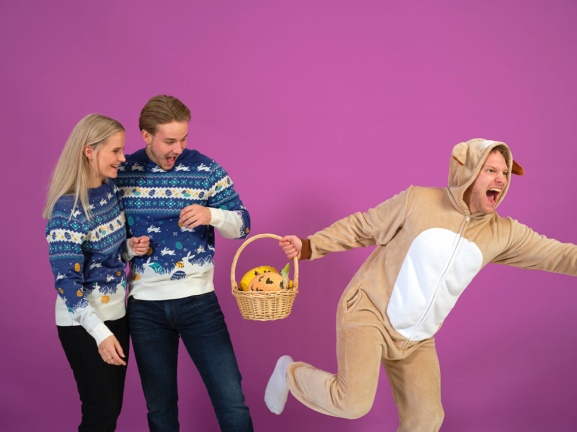 En mand og en dame kigger ned mod en påskehare, som løber fra dem.