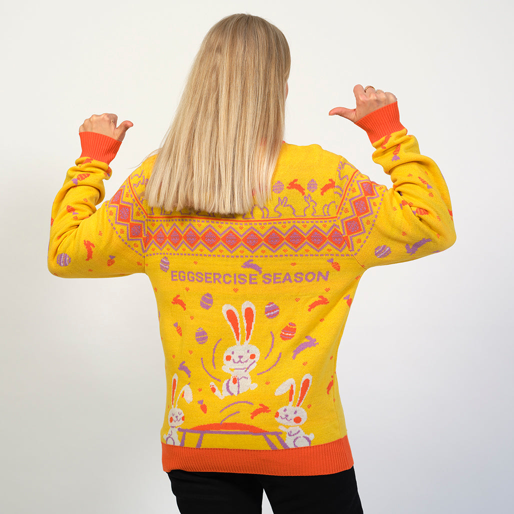 En kvinde med ryggen til peger på sin gule påskesweater.