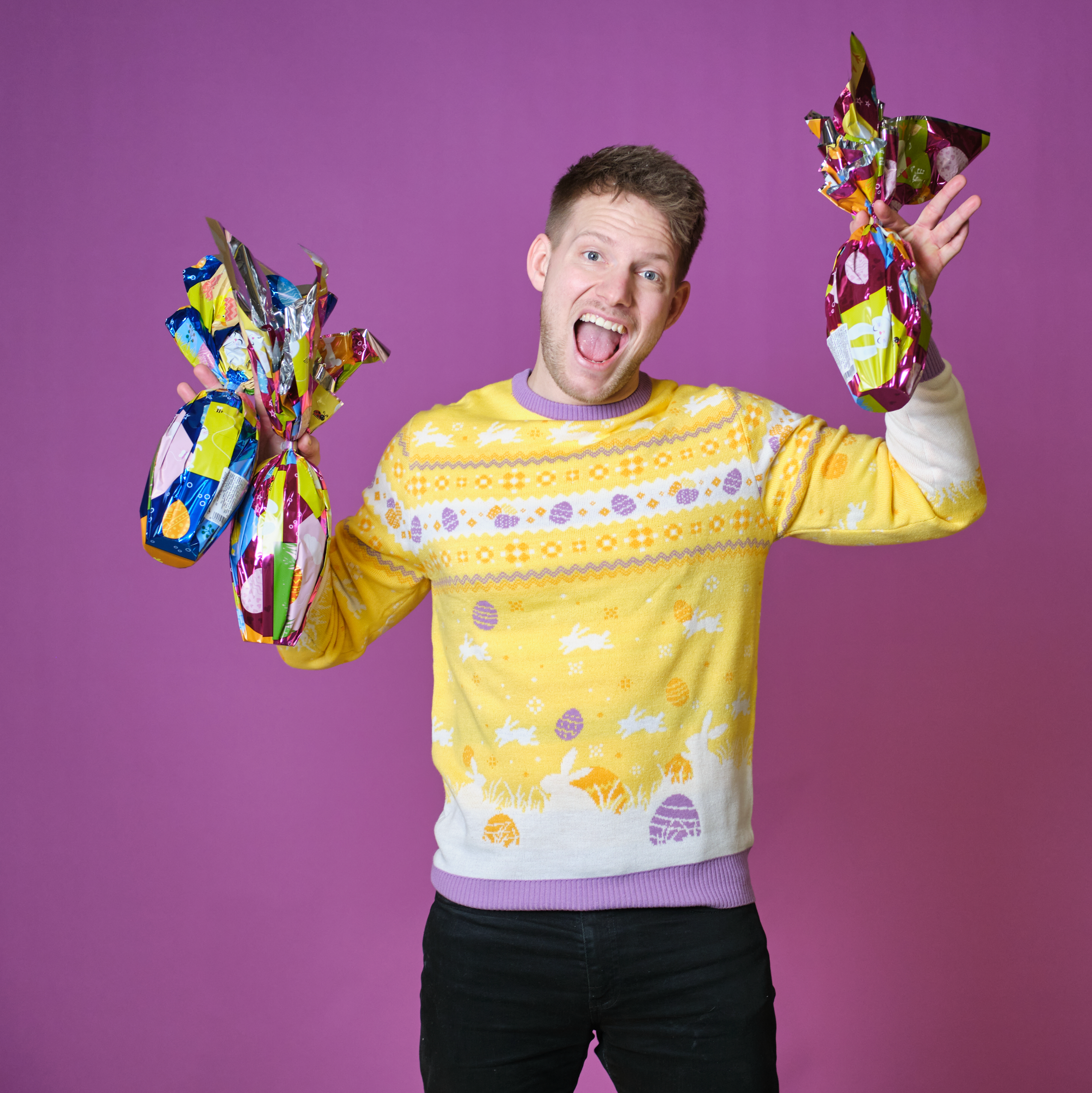 En mand står i en påskesweater og poserer med chokoladepåskeæg.